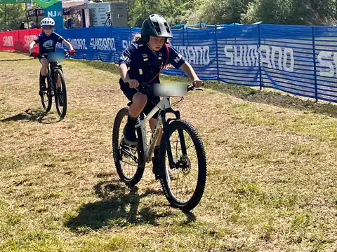 A young Shredders rider pedals across the grass after finishing a race.