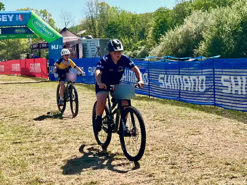 A Shredders rider pedals toward the camera after crossing the finish line at a New Jersey league race.