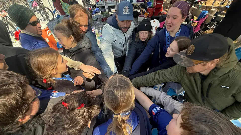 Shredders riders, coaches and parents stack hands in a team huddle before a race.
