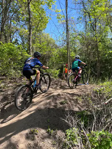 Shredders riders climb a dirt trail through the woods during practice.