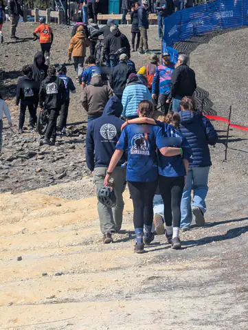 Two Shredders riders walk arm in arm up the race course, surrounded by teammates and families.